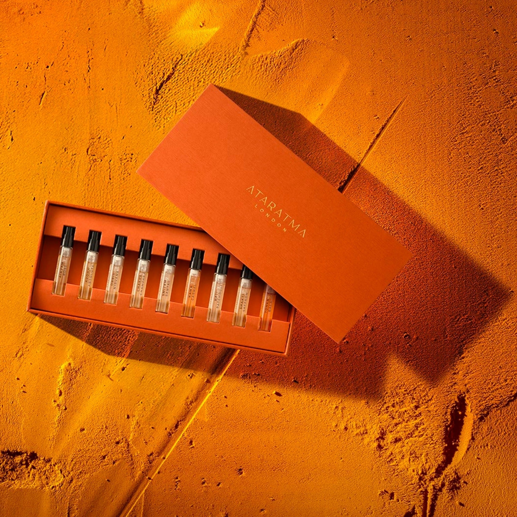 Set of perfume samples in an orange box on a textured orange surface